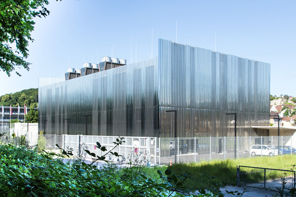 Questo magazzino centro dati a Basilea ha un involucro frastagliato di pannelli d'acciaio perforati e pieni che offrono riflessi sfumati del cielo. Edifici in acciaio pre-ingegnerizzati per data center.